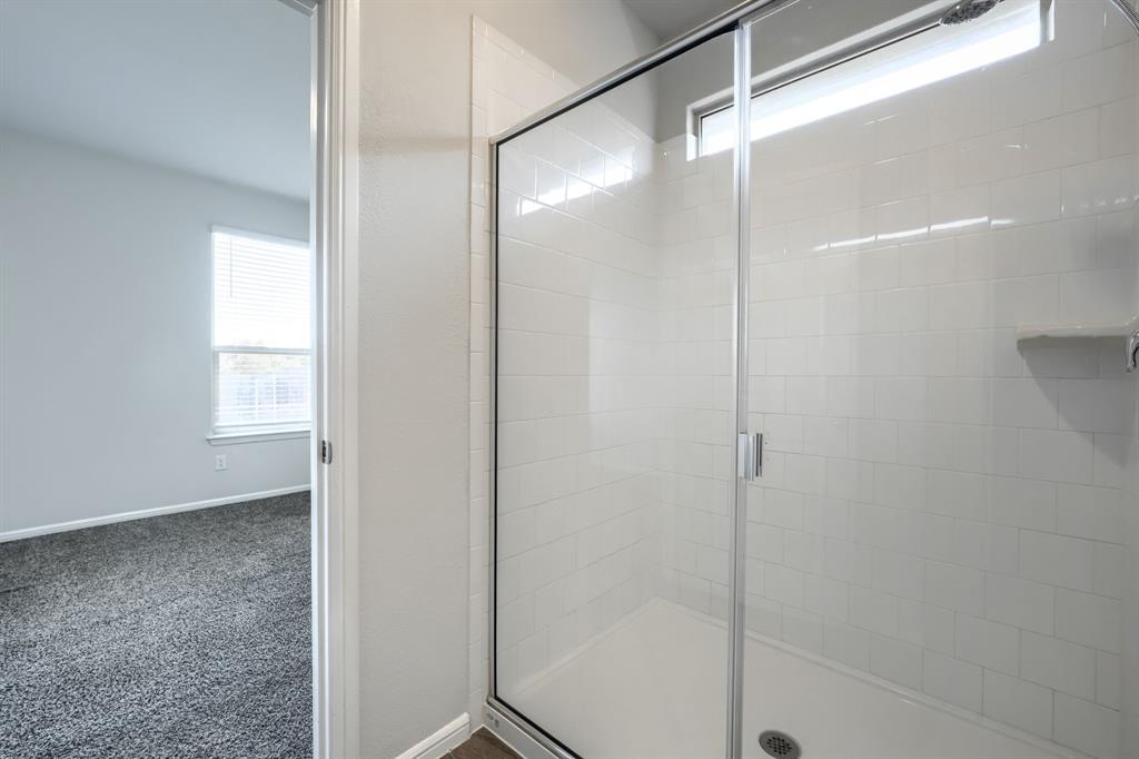 Walk-in shower featuring white subway tile surround, frameless glass door, integrated soap niche, and transom window