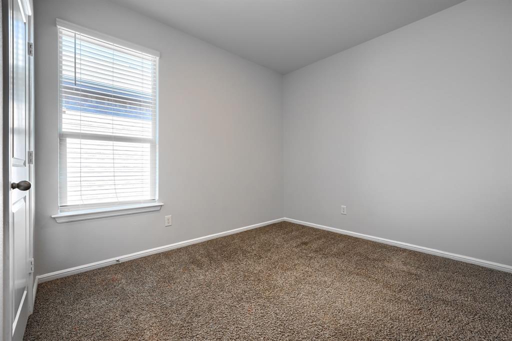 Neutral-toned room featuring neutral carpeting, a window with installed horizontal blinds, and a paneled interior door