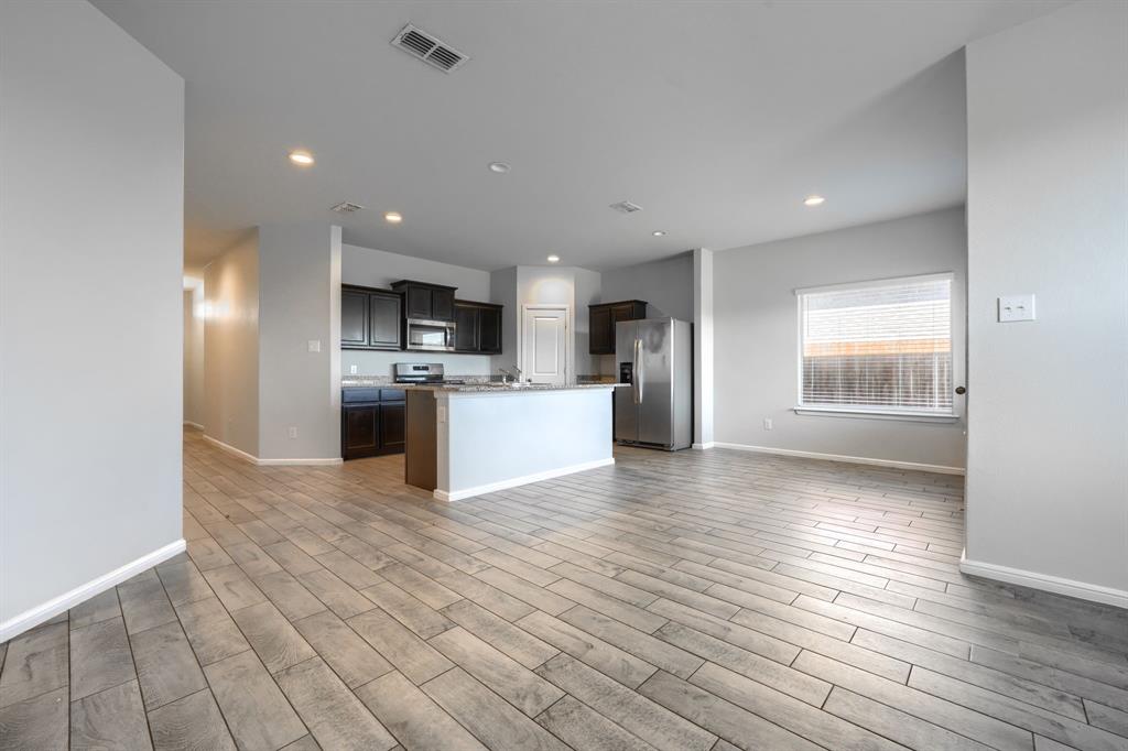 Open-concept interior featuring wood-finish flooring, dark cabinetry, a kitchen island, recessed lighting, and stainless steel appliances
