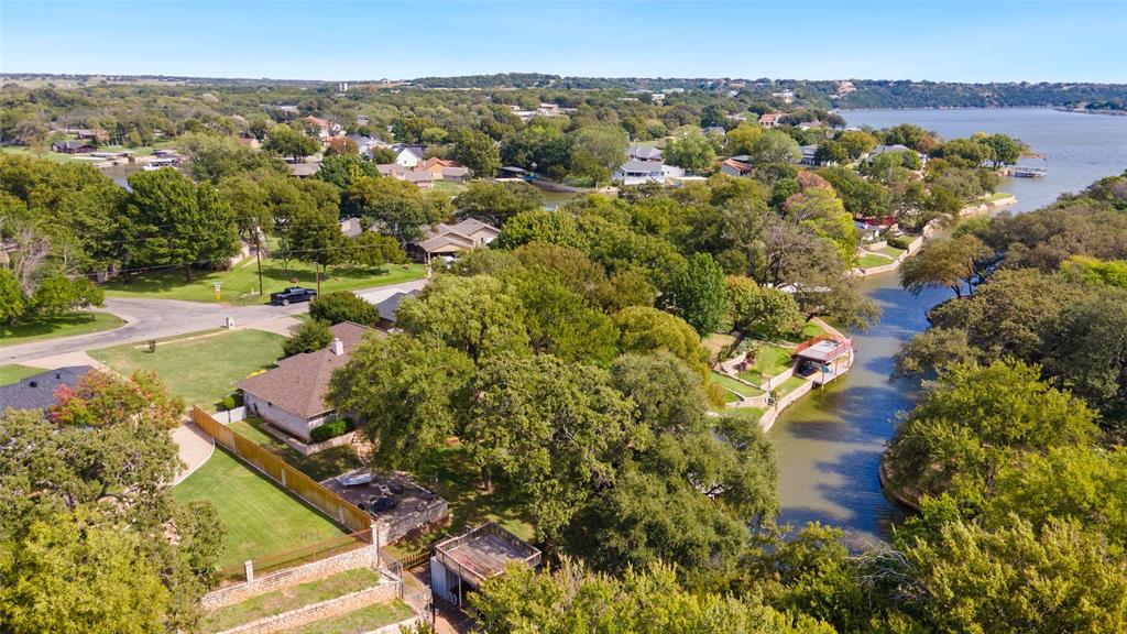 Waterfront property featuring a private boat dock, terraced stone retaining walls, mature trees, and expansive grassy grounds
