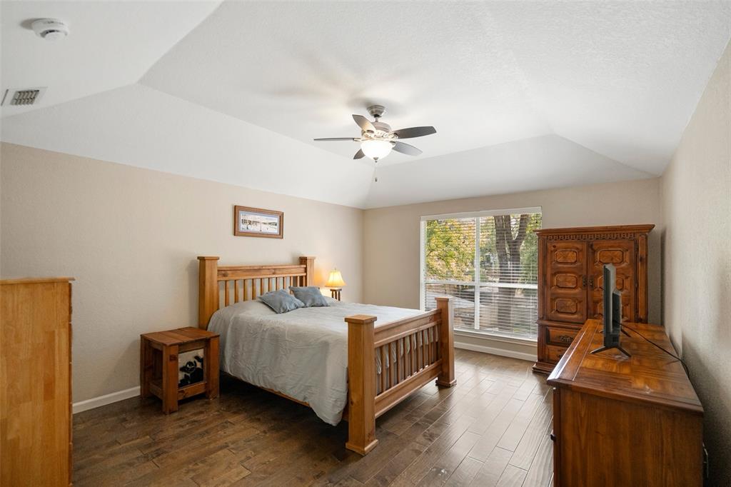 Primary bedroom with ceiling fan and wood-finish flooring and large windows overlooking the canal