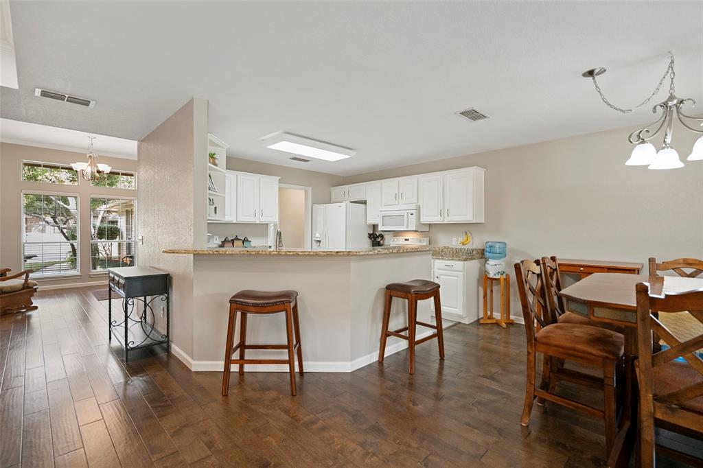 Kitchen featuring white cabinetry, a granite breakfast bar, wood-finish flooring, and a multi-light chandelier in the breakfast nook