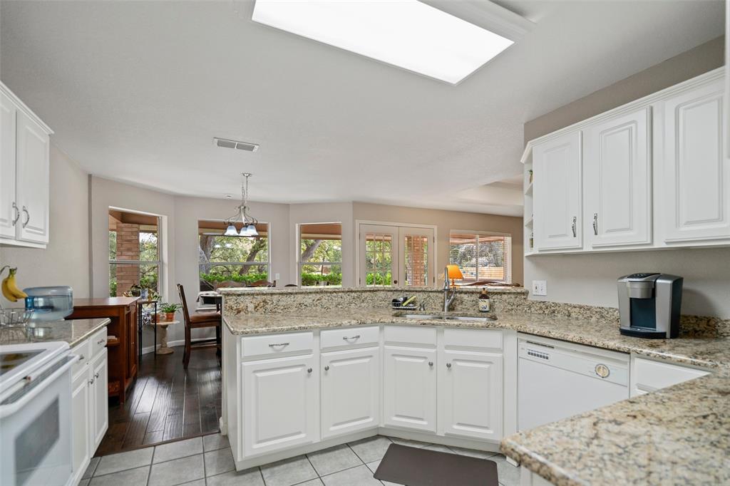 Kitchen featuring white cabinetry, granite countertops, double-basin stainless steel sink, and tile flooring