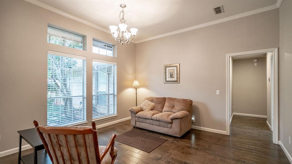 Dining room featuring wood-finish flooring, crown molding, multi-pane windows with transoms, and a classic chandelier