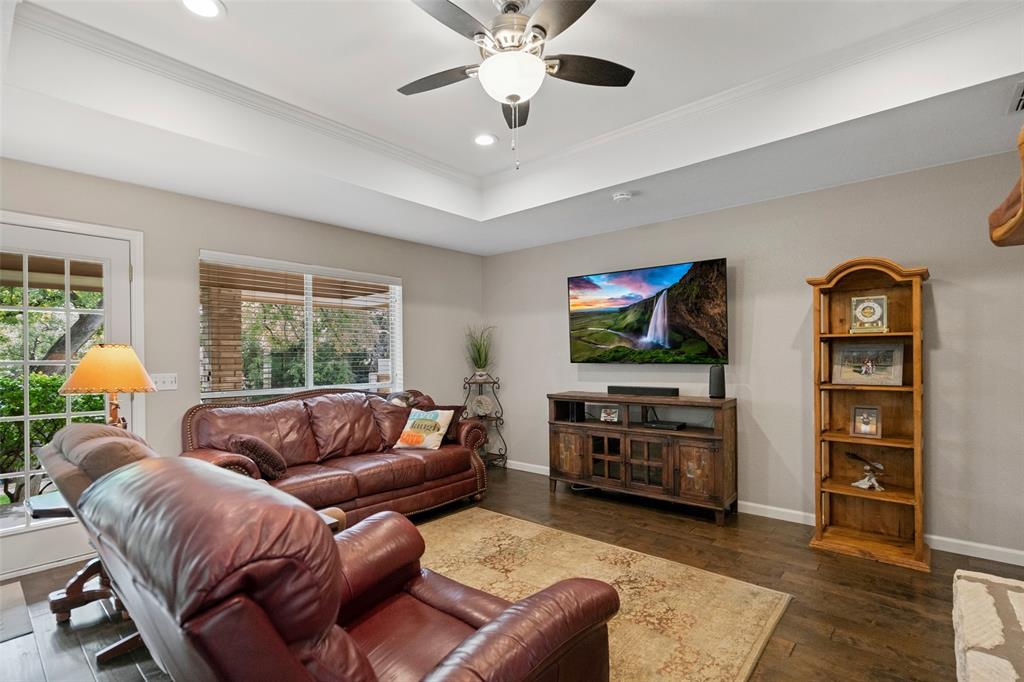 Tray ceiling featuring a ceiling fan with integrated lighting, wood-finish flooring, and recessed ceiling lights