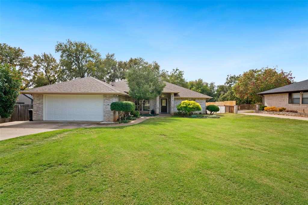 Single-story brick exterior featuring an attached two-car garage, and a manicured front lawn with mature landscaping