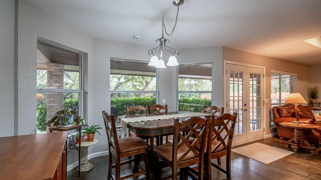 Breakfast area featuring bay windows, wood-finish flooring, a pendant light fixture, and glass-paneled french doors to access covered rear porch