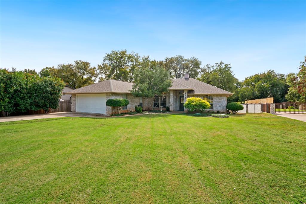 Single-story brick exterior with an attached two-car garage, and an expansive front lawn with mature landscaping