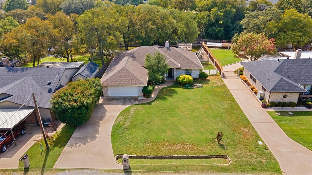 Single-story residence featuring a brick and stone facade, multi-gable roofline, two-car garage, and expansive front lawn with a concrete driveway
