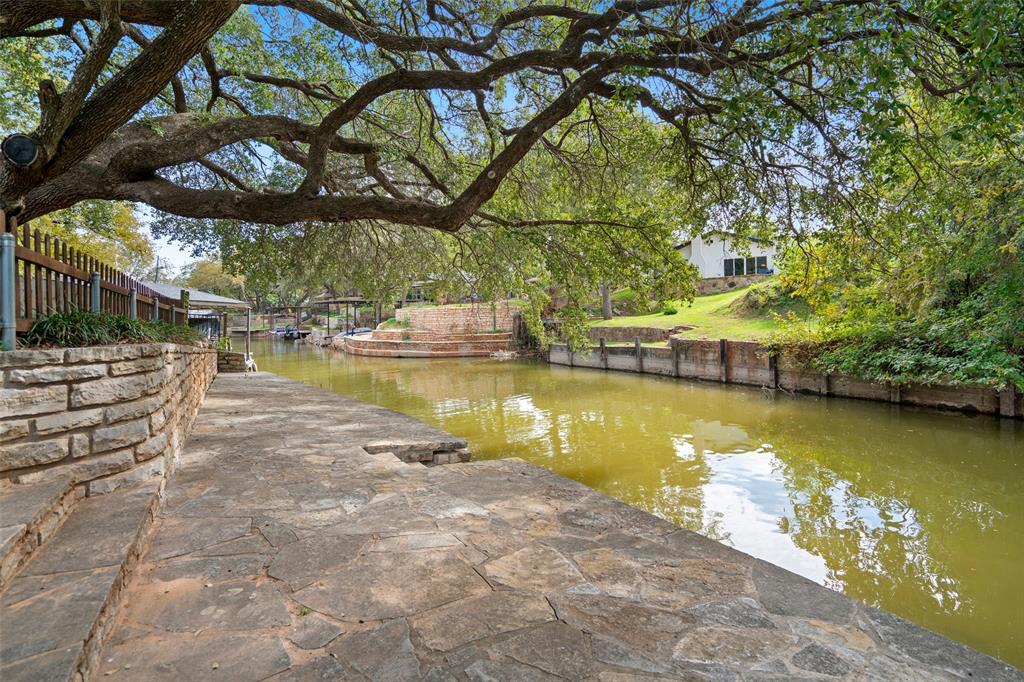 Waterfront view property featuring a flagstone and stacked stone retaining walls, and mature canopy trees