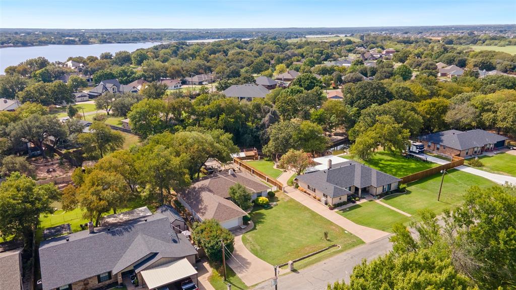 Aerial perspective of a residential neighborhood featuring established tree canopy, manicured lawns, and proximity to Lake Granbury mainbody