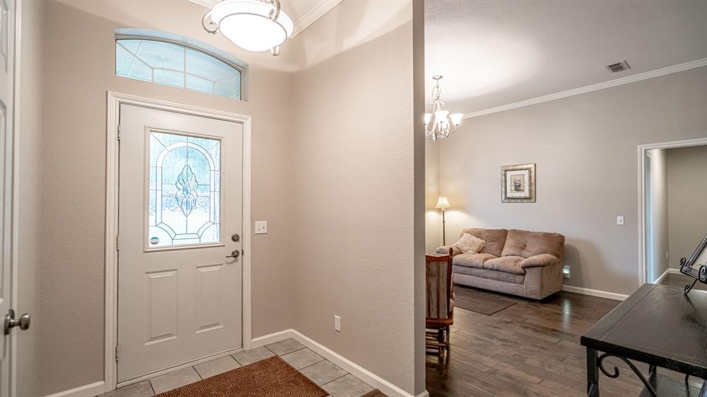 Entryway featuring an arched transom window, a glass-panel door, ceramic tile flooring, and crown molding