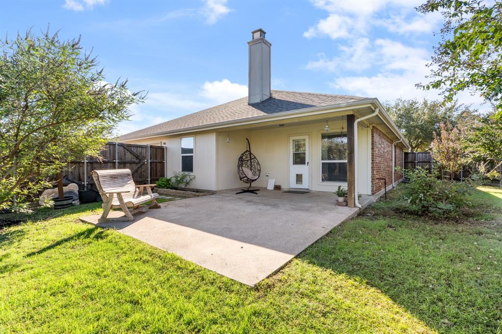 The large backyard features a large patio, multiple trees, and a Board on Board fence
