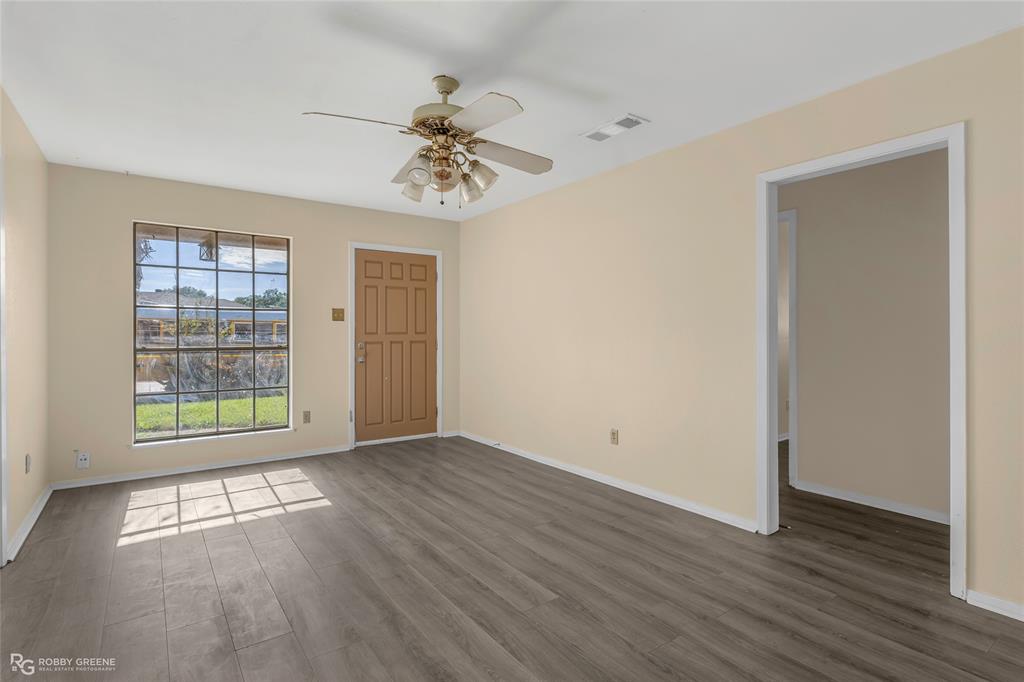 Interior room featuring wood-finish flooring, a multi-pane grid window, and a ceiling fan with integrated lighting