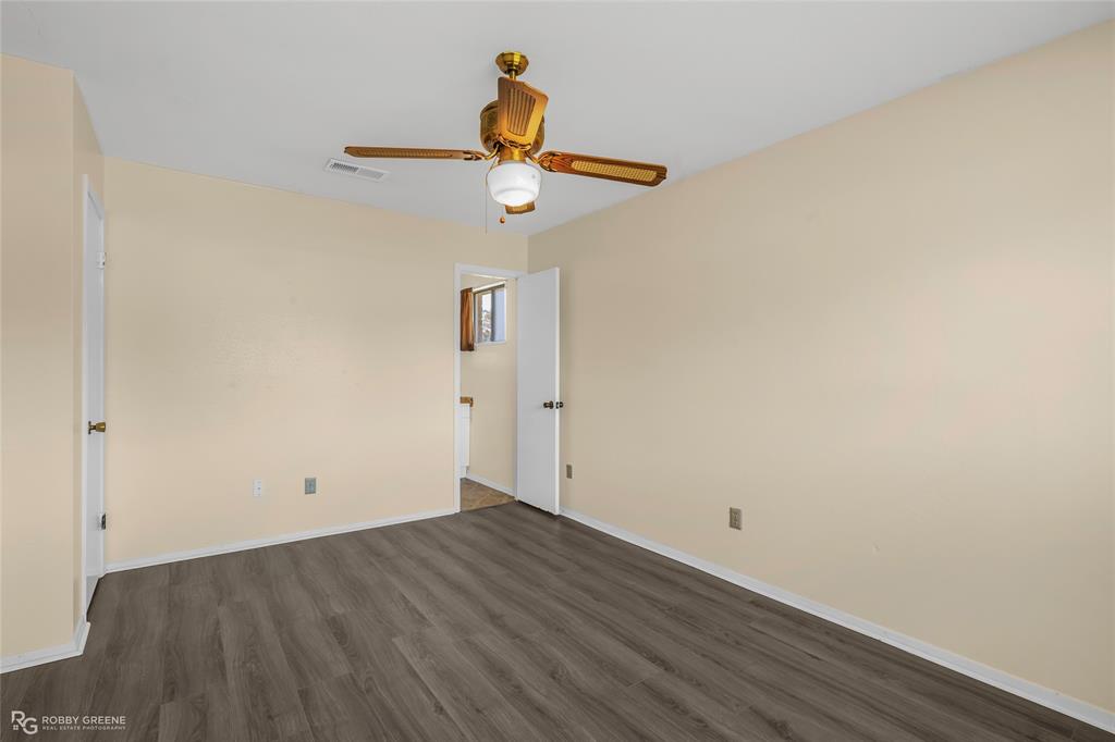 Neutral interior space featuring wood-finish flooring, a ceiling fan with integrated lighting, and white interior doors