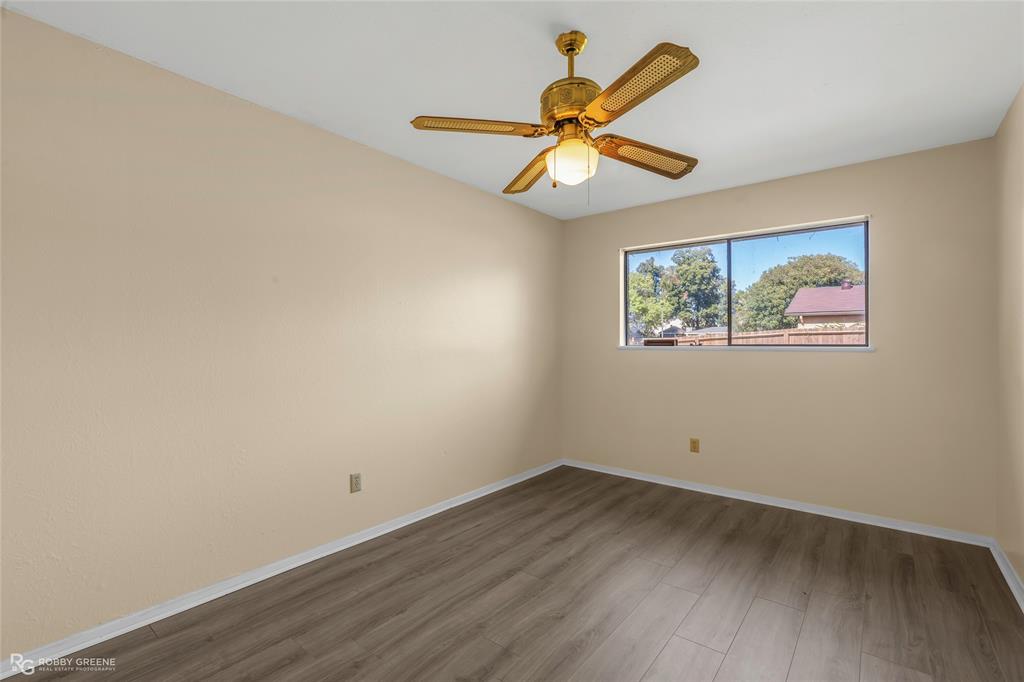 Room featuring wood-finish flooring, a horizontal sliding window, and a ceiling-mounted fan with integrated light fixture