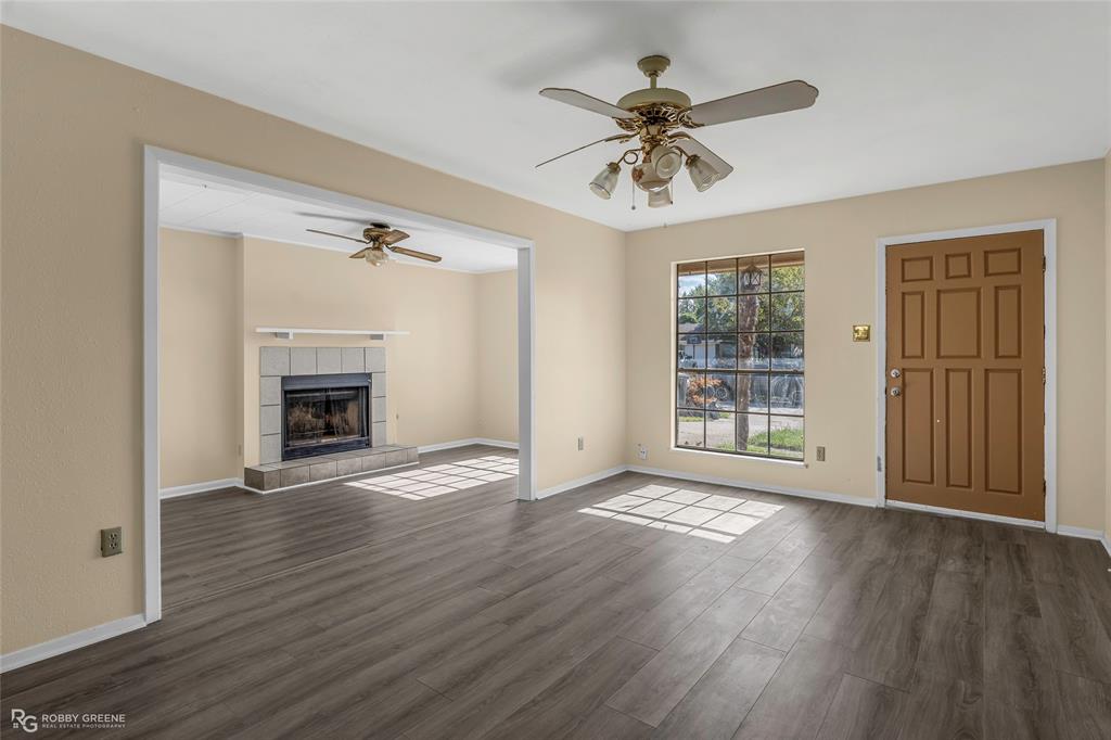 Wood-finish flooring, masonry fireplace with a mantel, grid-pattern window, ceiling fans, and a paneled entry door