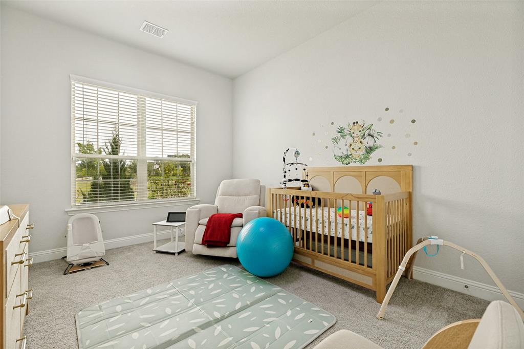 Neutral interior featuring light-toned wall-to-wall carpeting, large window with horizontal blinds, and a built-in cabinetry unit