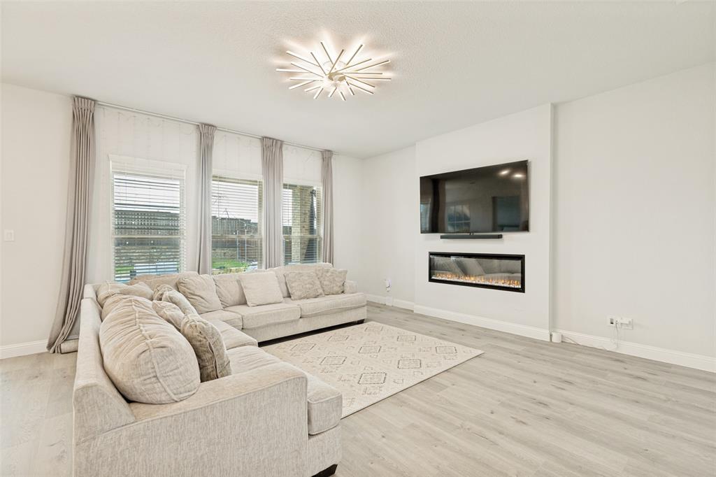 Living area featuring wood-finish flooring, a linear electric fireplace, and a contemporary starburst chandelier