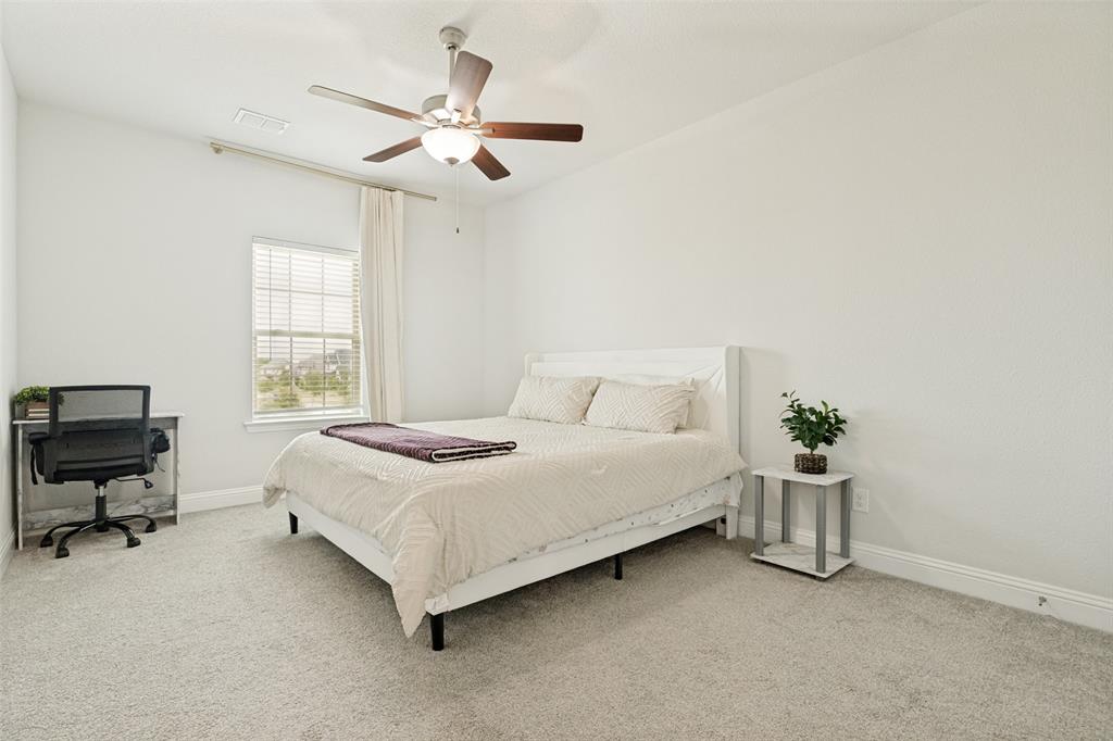 Neutral-toned carpeting, multi-blade ceiling fan with integrated lighting, and window featuring horizontal blinds