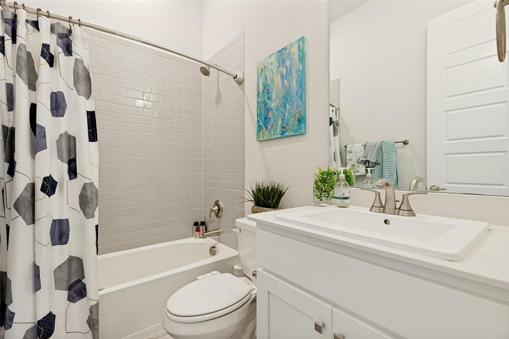 Bathroom featuring a white vanity with a rectangular sink, brushed nickel faucet, subway tile tub surround, and a large wall-mounted mirror