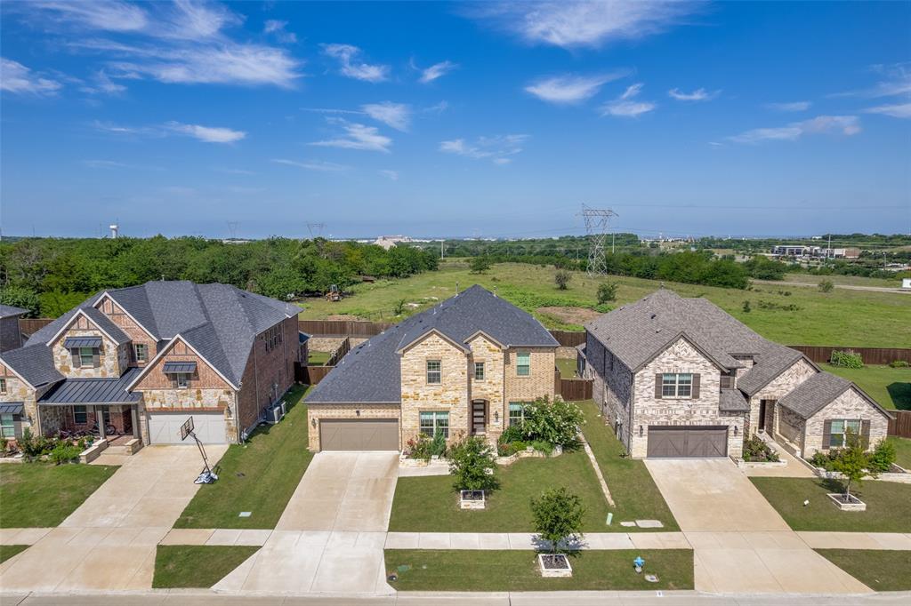 Multi-story exterior featuring a stone and brick facade, steeply pitched asphalt shingle roof, attached multi-car garage, concrete driveway, and professional landscaping