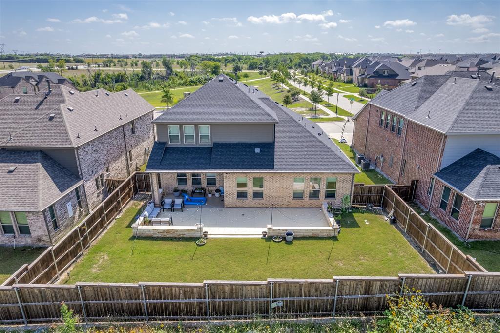 Backyard featuring a paved stone patio, retaining wall, manicured lawn, and wood privacy fencing