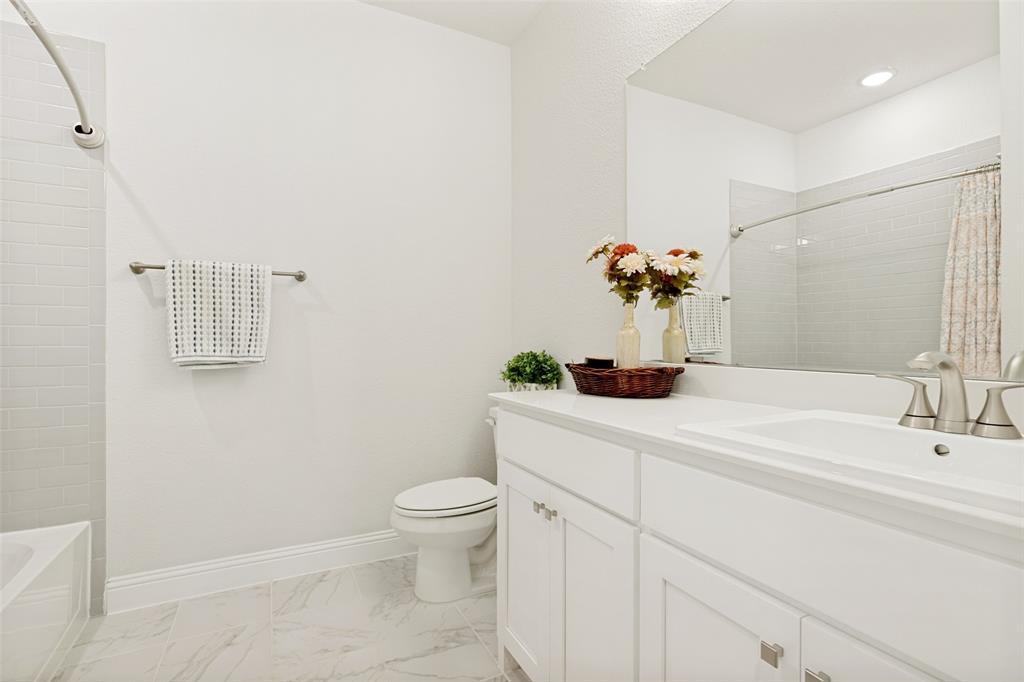 Bathroom featuring white shaker-style cabinetry, an integrated sink with polished metal fixtures, a large wall-mounted mirror, and tile flooring with a neutral pattern