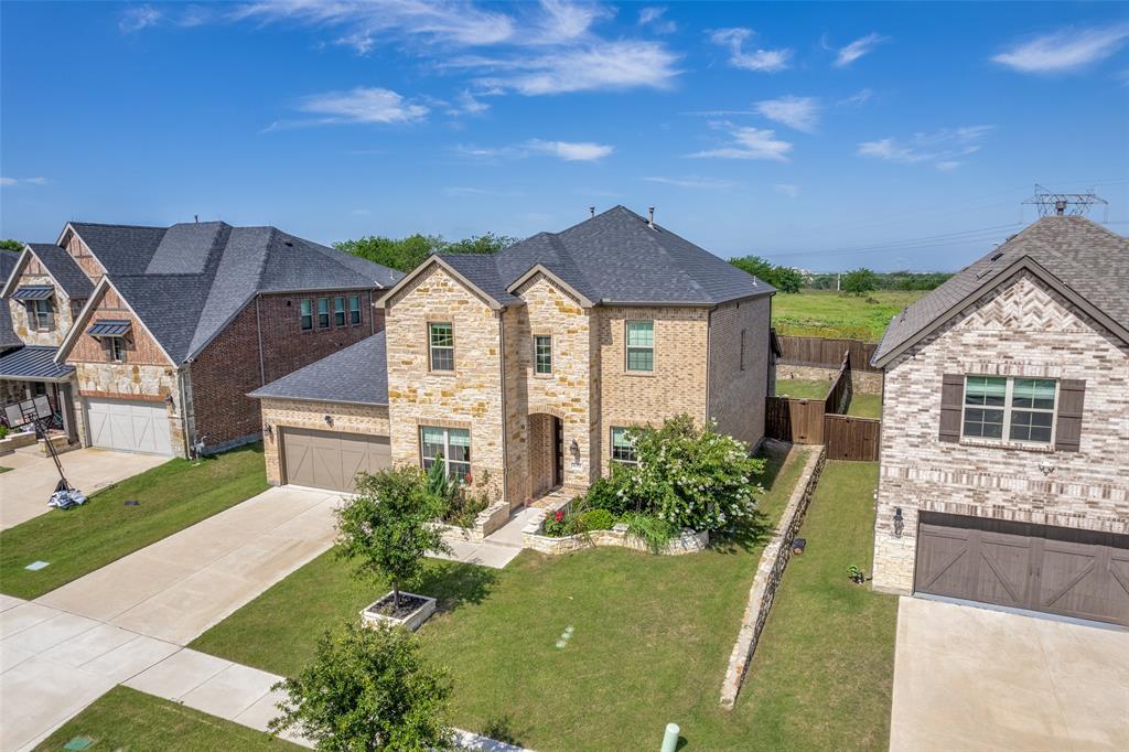 Two-story residence featuring a mixed stone and brick facade, gabled rooflines, an attached two-car garage, and a landscaped front yard with stone retaining walls