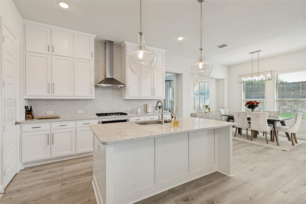 Kitchen featuring white cabinetry, quartz countertops, a stone hexagon-patterned backsplash, stainless steel chimney-style range hood, and wood-finish flooring