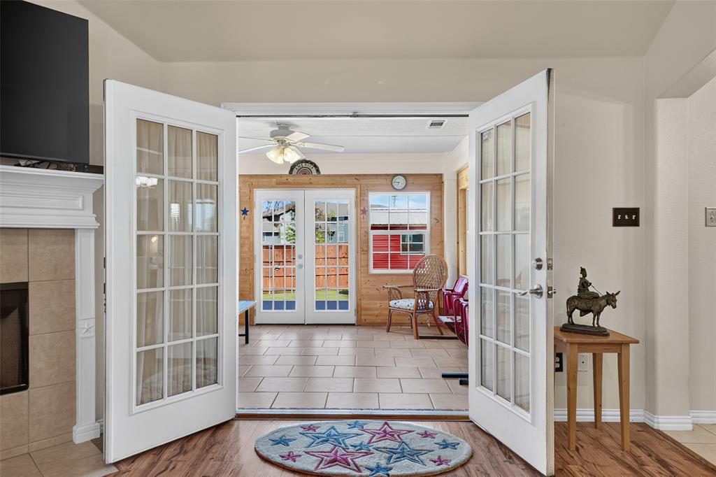 Double French doors with glass panes lead to this beautifully remodeled sunroom with wood-paneled walls,  ceiling fan and French doors to the backyard.