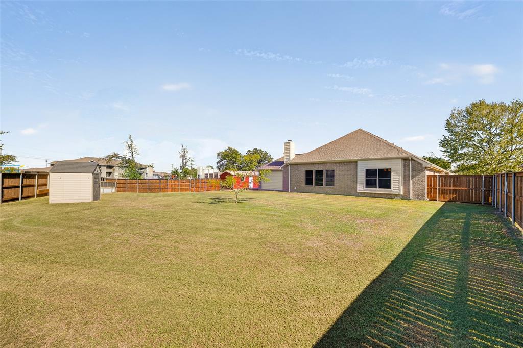 Expansive backyard featuring  the detached structures and a cute mimosa tree flourishing in the middle of the yard.  MORE than enough room for a huge outdoor living center!