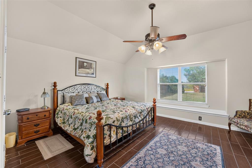 Spacious primary bedroom featuring vaulted ceilings with fan, abundant natural light, and a cozy window seat overlooking the backyard.