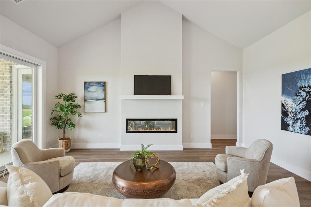 Vaulted ceilings, linear fireplace with a minimalist mantel, and wood-finish flooring