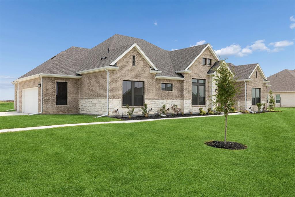 Traditional residence featuring brick and stone masonry, multi-gabled roofline, dark-trimmed windows, and an attached multi-car garage