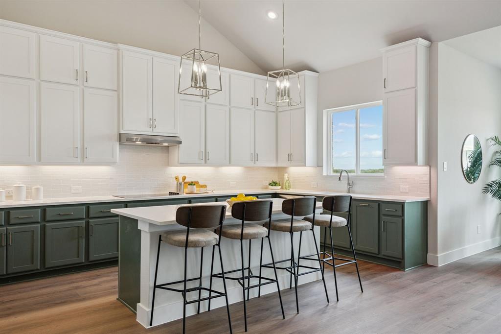 Kitchen featuring two-tone cabinetry, central island with seating space, stainless steel range hood, stone-finish countertops, and wood-finish flooring