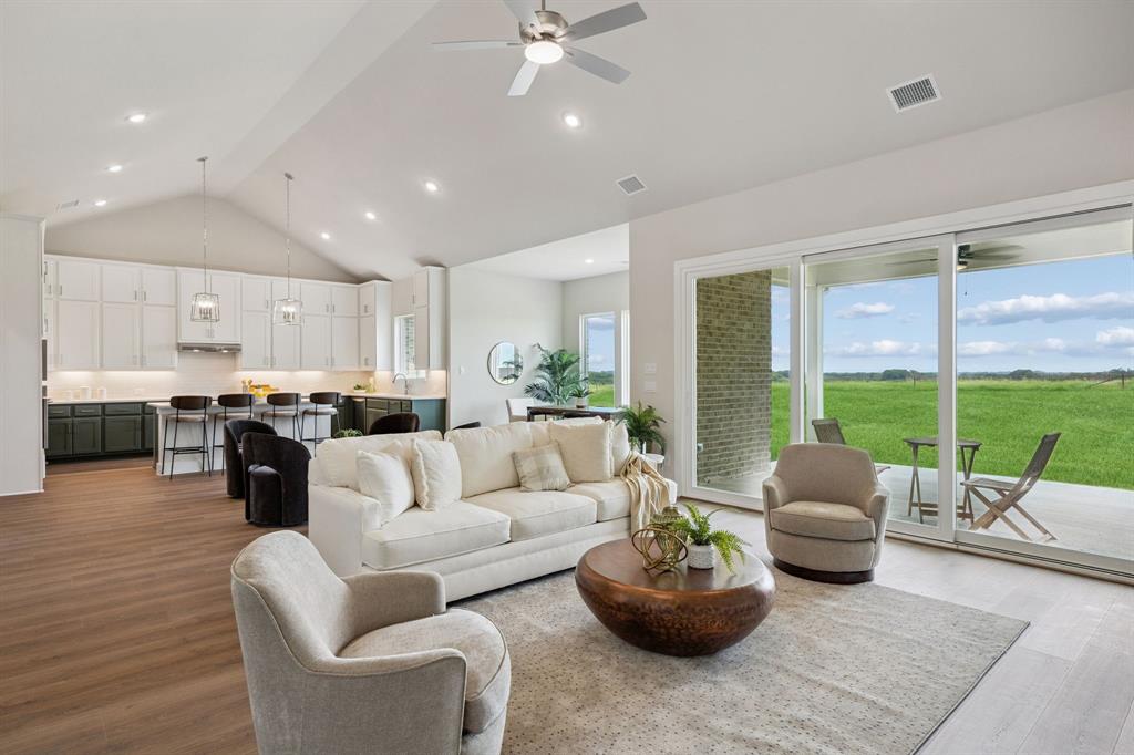 Vaulted ceilings, open-concept kitchen with white cabinetry, wood-finish flooring, recessed lighting, and expansive glass sliding doors