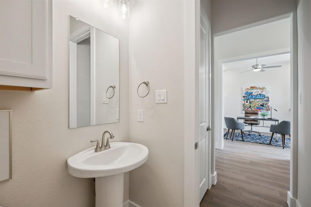 White pedestal sink featuring a polished nickel faucet, wall-mounted rectangular mirror, and overhead decorative lighting fixture