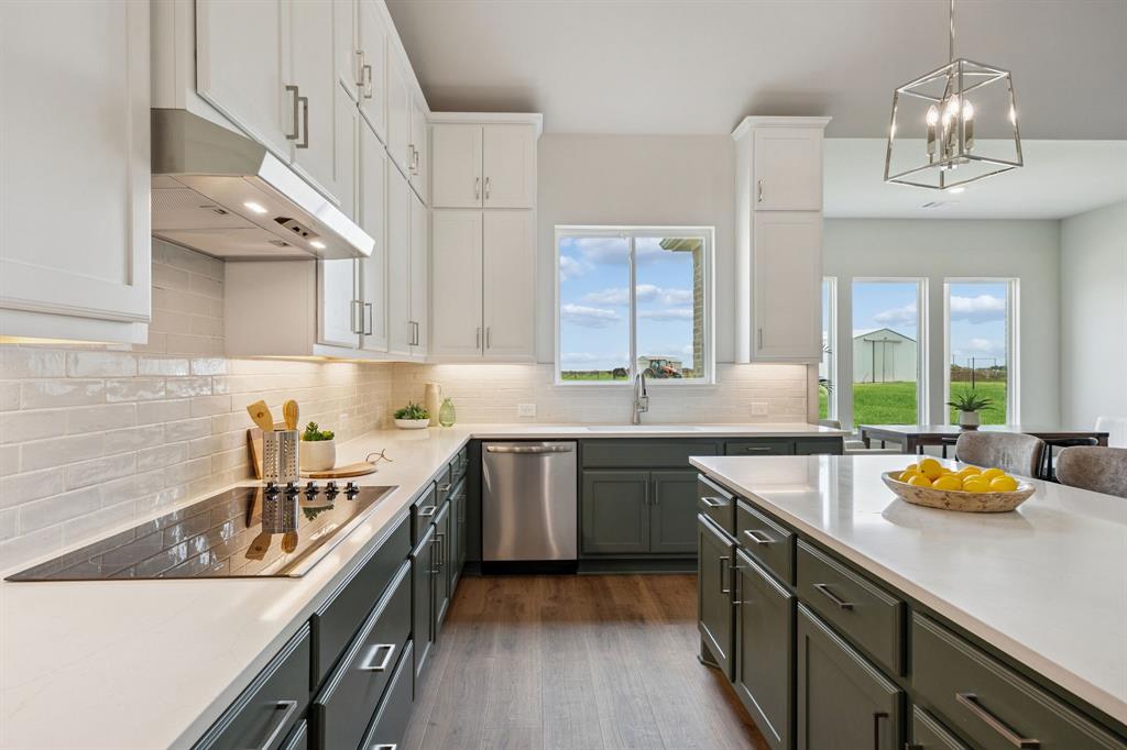 Kitchen featuring dual-tone cabinetry, quartz countertops, white subway tile backsplash, stainless steel appliances, and wood-finish flooring