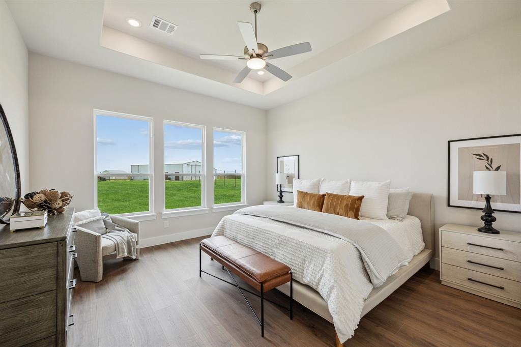Tray ceiling, wood-finish flooring, ceiling fan, and large windows with exterior landscape exposure