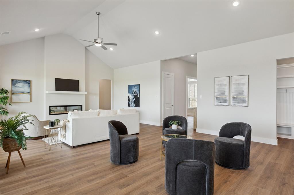 Vaulted ceilings, linear fireplace with a mantel, wood-finish flooring, recessed lighting, and built-in shelving