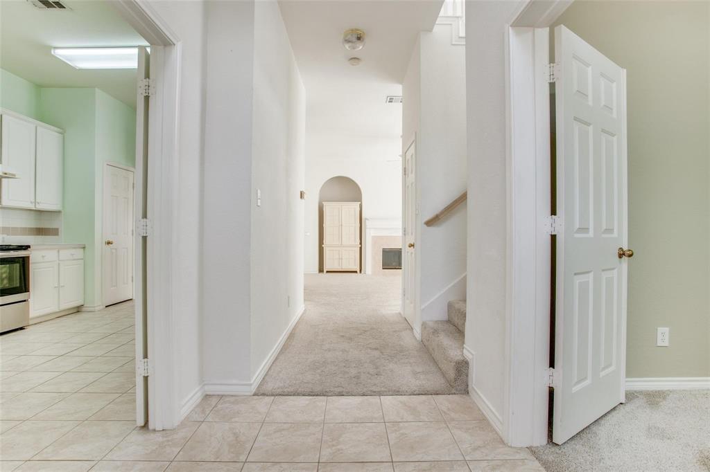 Interior entryway featuring tile flooring, six-panel interior doors, carpeted staircase, and an arched architectural opening