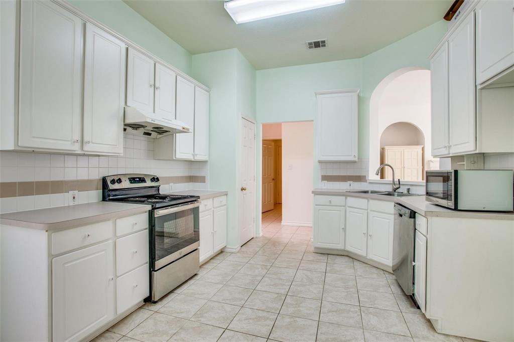 Kitchen featuring white cabinetry, stainless steel oven, tile flooring, ceramic tile backsplash, and a pass-through arched opening