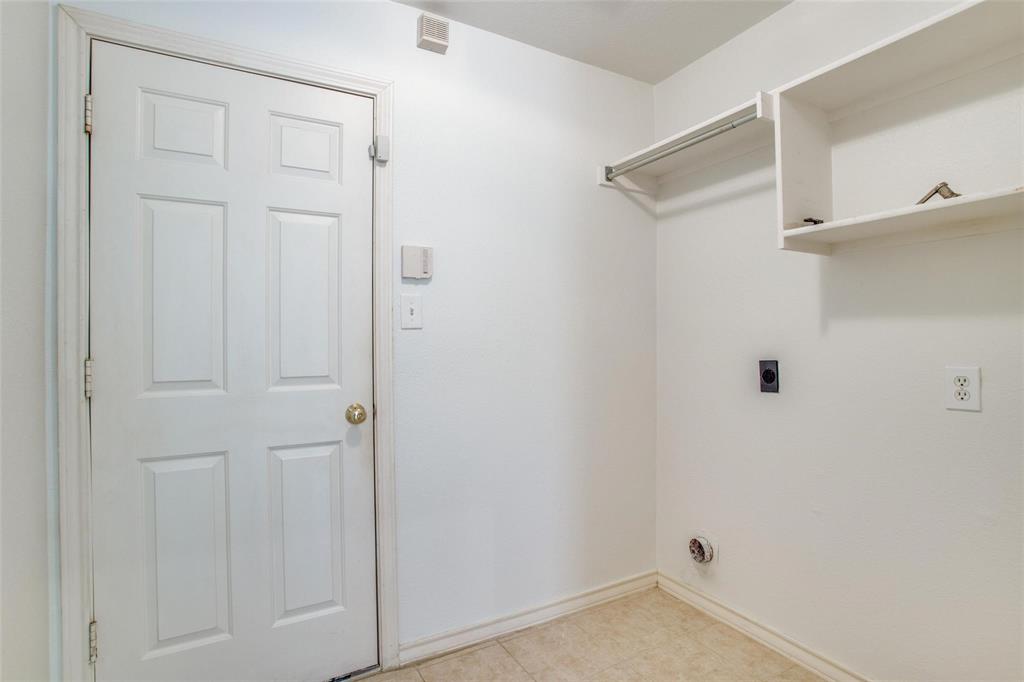 Utility space featuring a six-panel door, built-in shelving with integrated hanging rod, and dedicated hookups