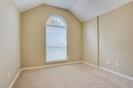 Vaulted ceiling featuring an arched window with neutral-toned wall paint and carpeted flooring