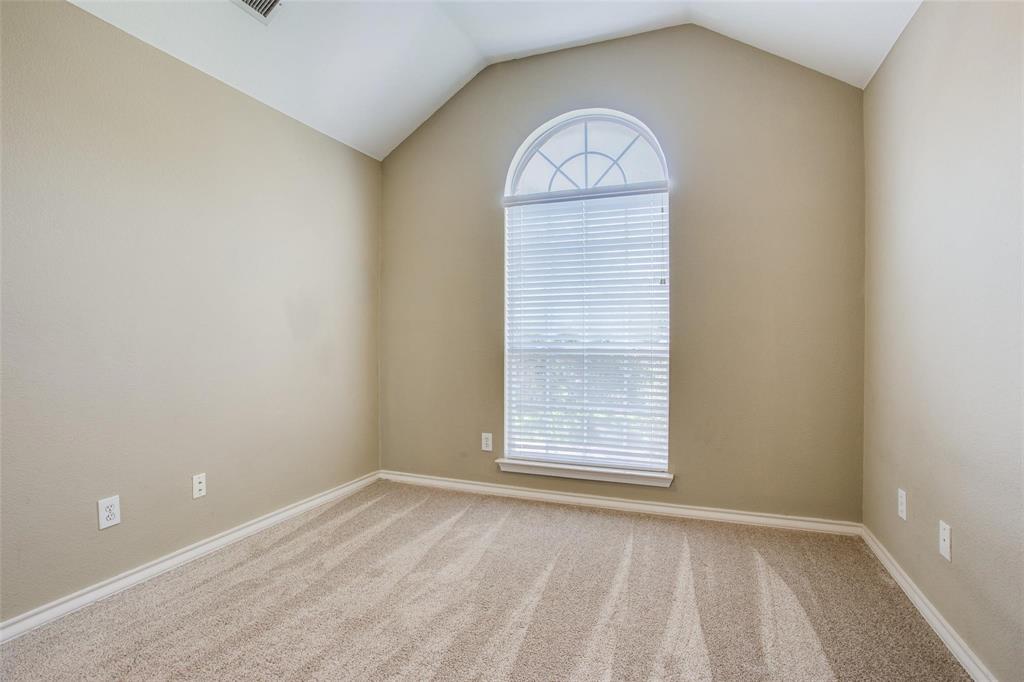 Room featuring a vaulted ceiling, neutral wall tones, carpeting, and a large window with an arched transom