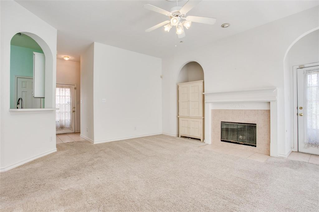 Living area featuring a fireplace with a masonry surround, arched architectural details, built-in cabinetry, and a ceiling fan