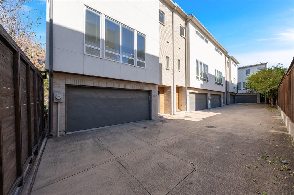 Multi-level exterior featuring light brick facade, oversized windows, and private garages with concrete driveway