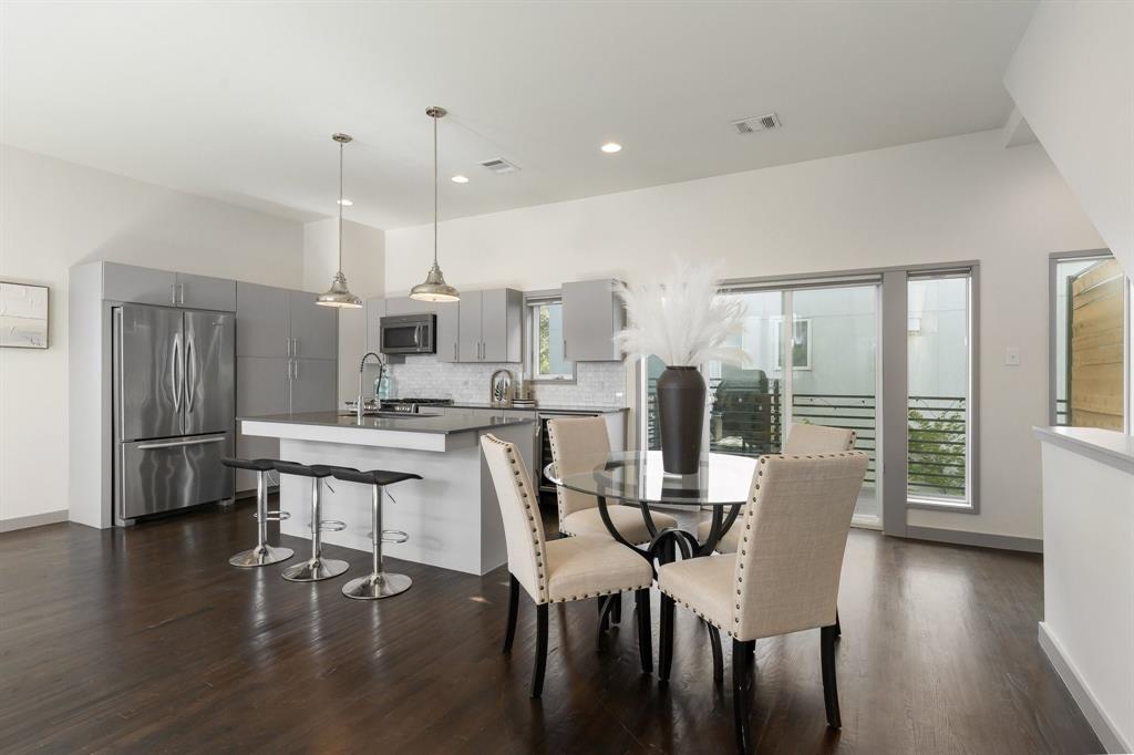 Kitchen featuring flat-panel cabinetry, a central island with a solid-surface countertop, stainless steel appliances, recessed lighting, and wood-finish flooring