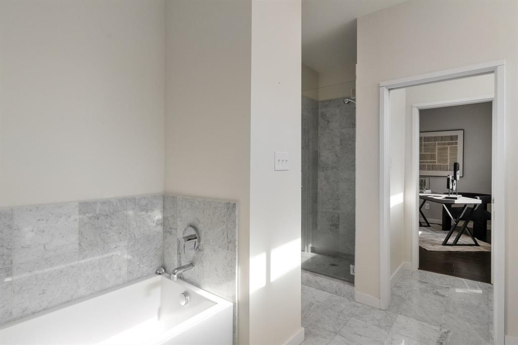 Bathroom featuring stone-tile flooring, a deep soaking tub with stone-tile surround, and a walk-in shower with a glass enclosure